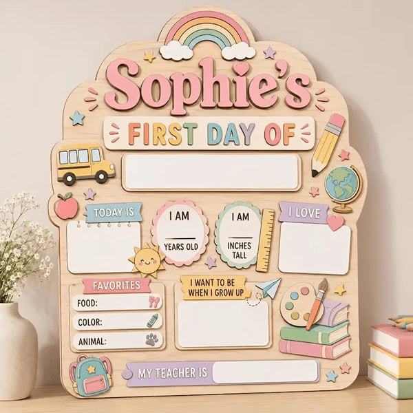 A wooden sign for a child's first day of school featuring illustrations like a school bus, rainbow, and various labels.