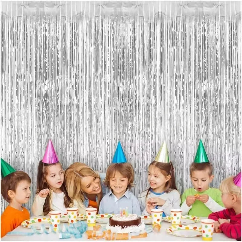 A festive backdrop featuring silver metallic foil tinsel fringe and a cake with candles.