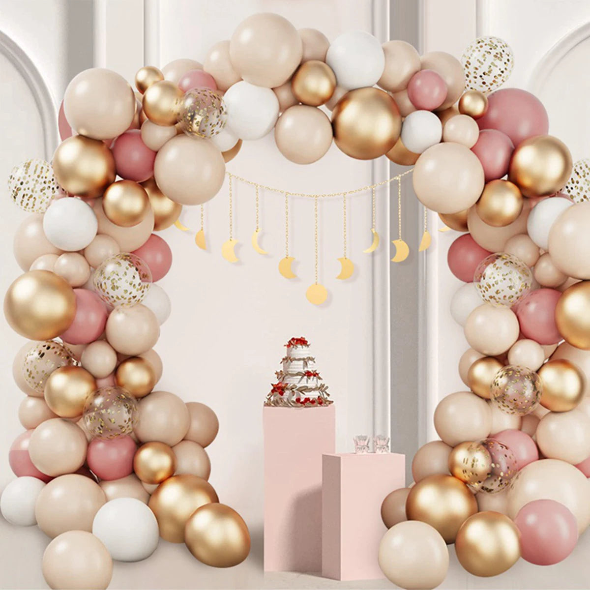 A floral arch made of pink and gold latex balloons with gold ribbons for a celebration backdrop.