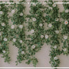 A lush green and white artificial eucalyptus garland draped across a wall for party decor.