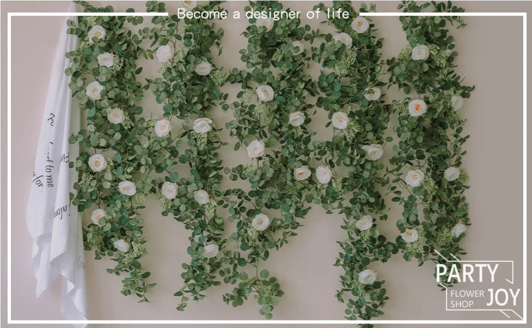 A lush green and white artificial eucalyptus garland draped across a wall for party decor.