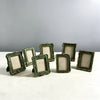 A collection of vintage baroque resin picture frames in olive green and gold accents displayed on a white surface.