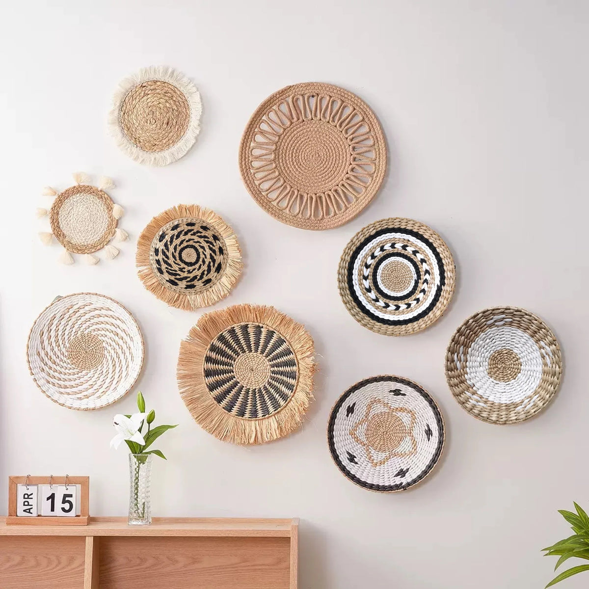 A collection of round boho straw wall hangings with woven tassels displayed on a white wall.