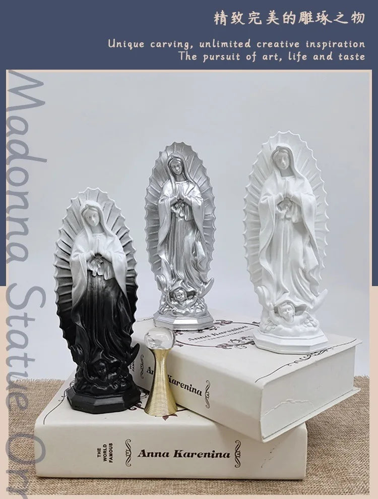 Three resin statues of Our Lady of Guadalupe in silver and white, displayed on a white book.
