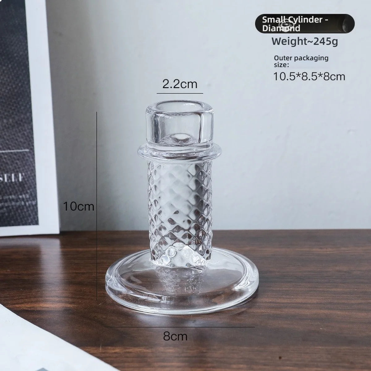 A clear glass pillar candle holder with a diamond pattern, shown standing on a round base.
