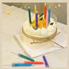 A round white cake decorated with yellow candles and green candles on a white platter.