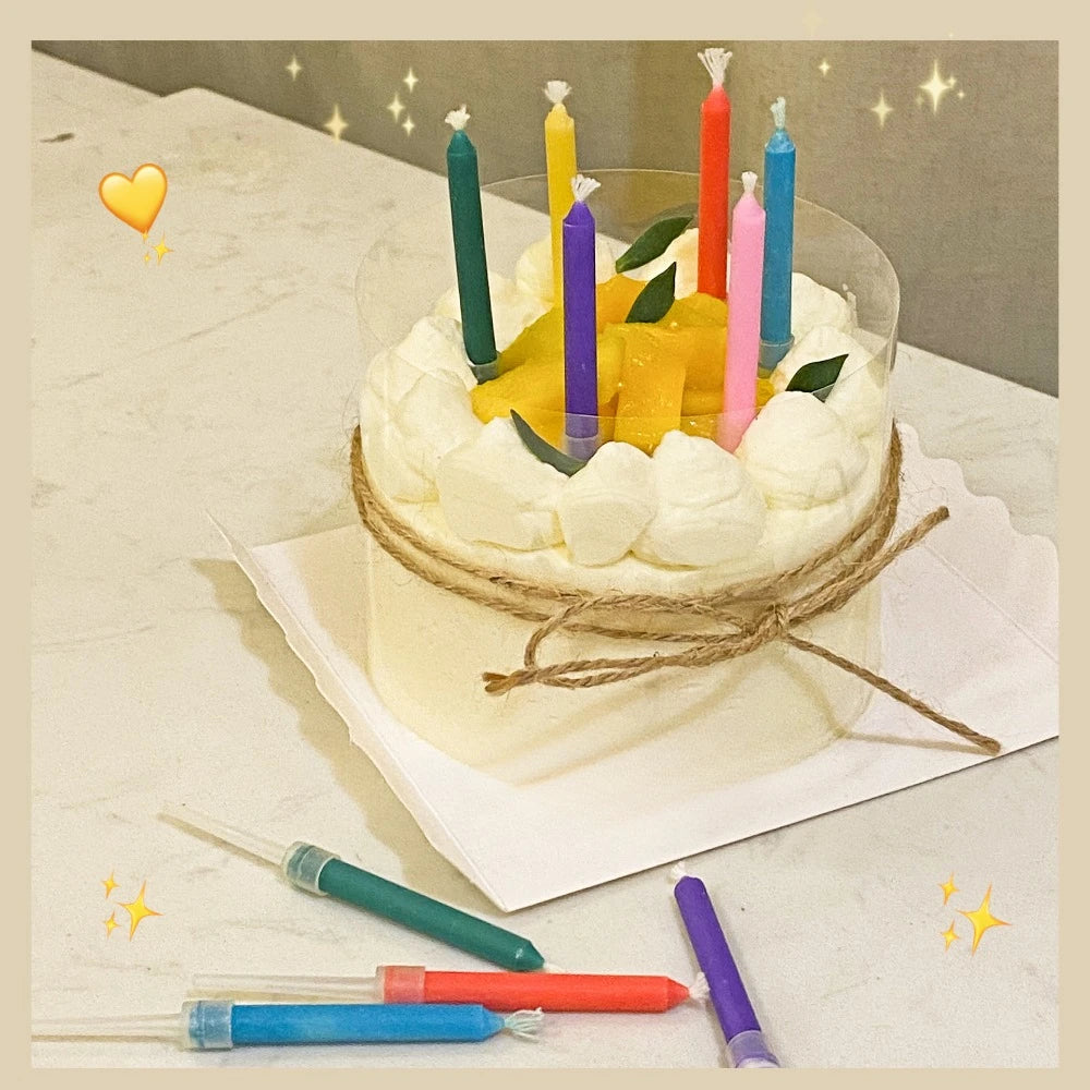 A round white cake decorated with yellow candles and green candles on a white platter.