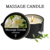 A black massage candle in a jar with a lit wick, featuring a gardenia flower design.