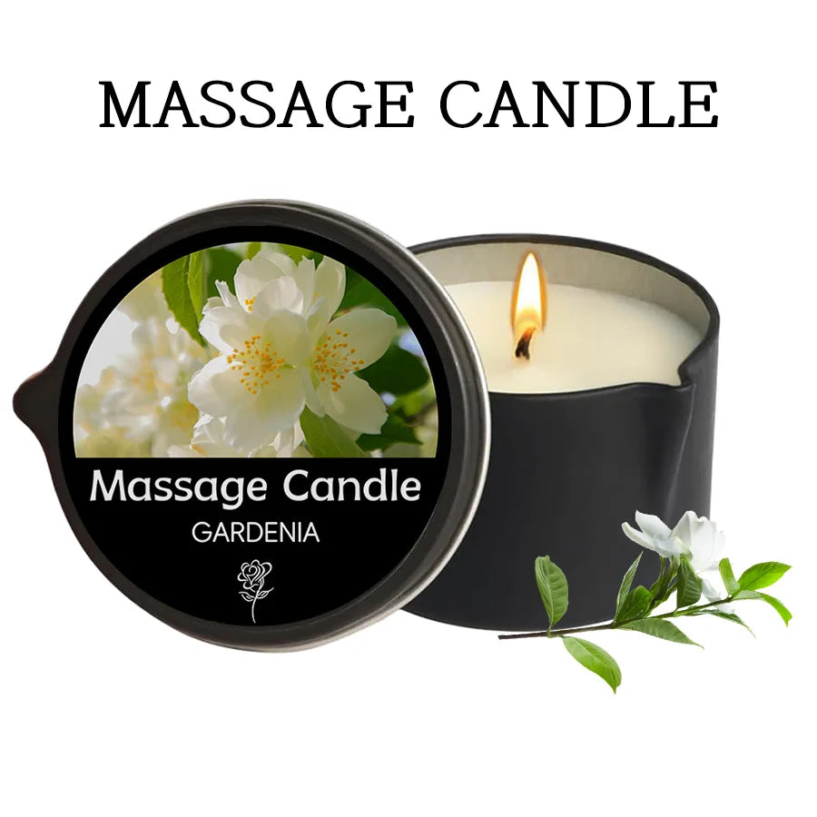 A black massage candle in a jar with a lit wick, featuring a gardenia flower design.