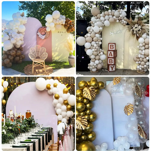 Exhibición de globos blancos y dorados con follaje, dispuestos sobre una mesa con un fondo de arco rosa.