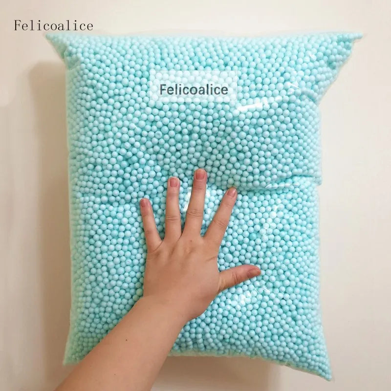 A hand is holding a light blue pastel foam bead pillow labeled Felicoalice.