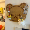A felt wall decor panel shaped like a brown bear face with large eyes, featuring hanging charms and a felt animal figure.