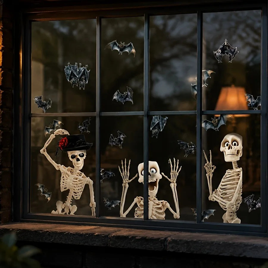 A window decorated with black silhouette stickers of skulls and bats against a dark background.