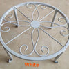 White decorative metal plant stand with a circular saucer design.