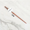 A brown metal magic wand replica with a metal core shown against a white marble background.