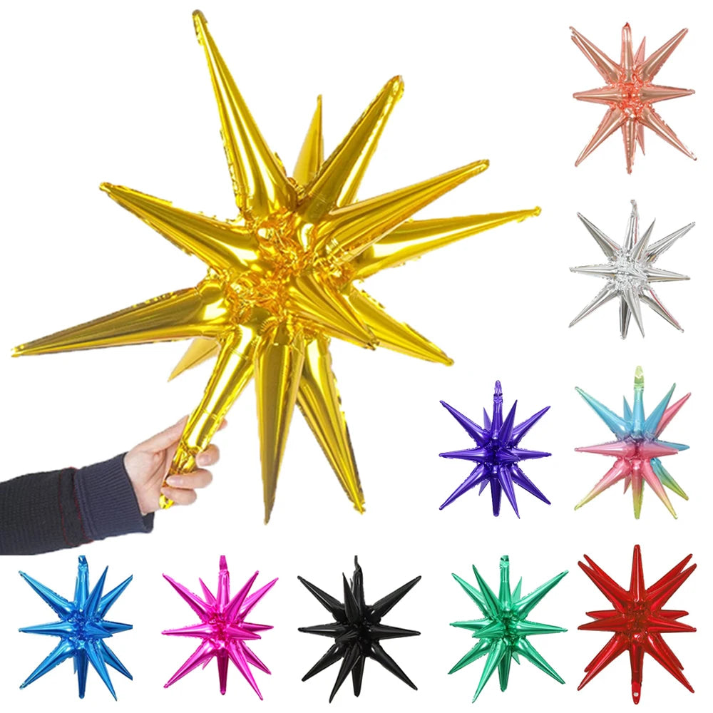 A hand holds a gold star burst foil balloon alongside several other colored star burst balloons.