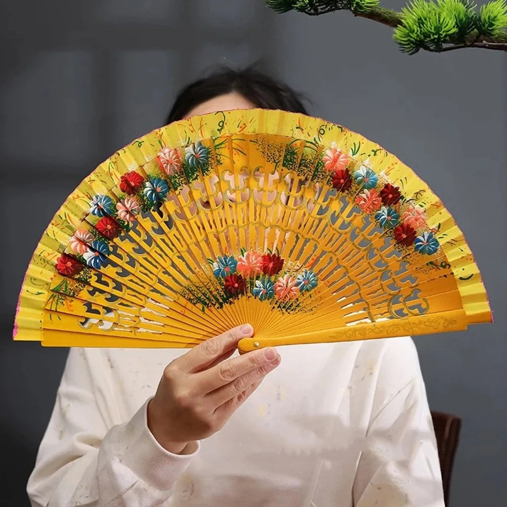 A hand-painted decorative folding fan with yellow and green petals and floral accents.