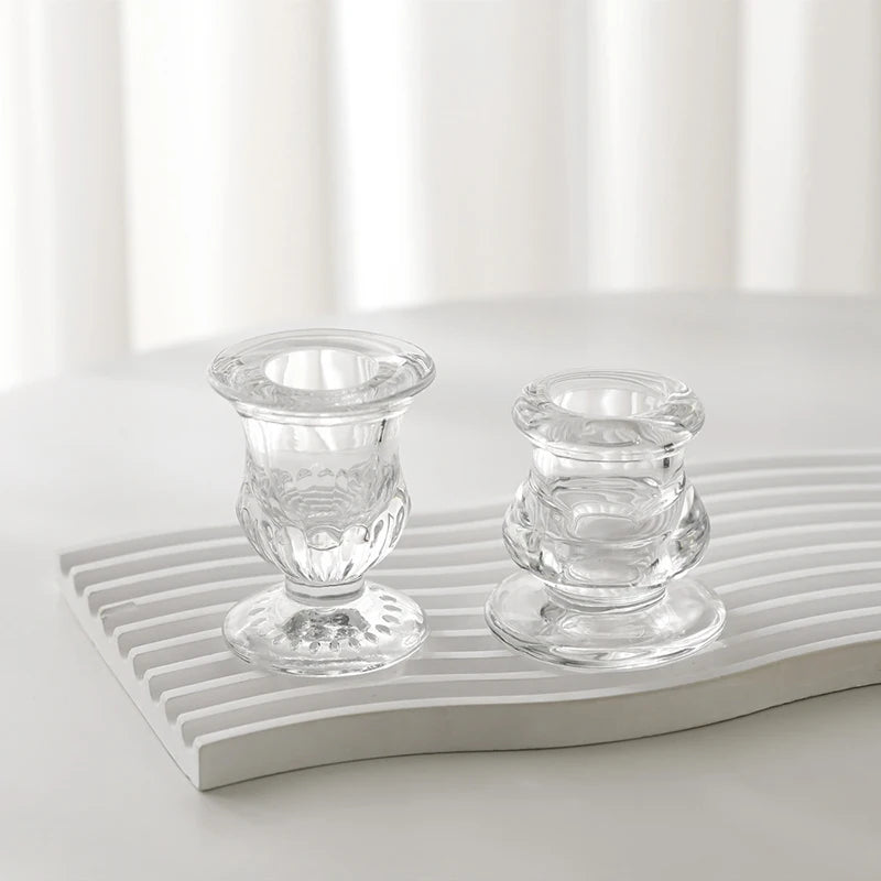 Elegant clear glass candle holder with a decorative candlestick design resting on a white ribbed tray.