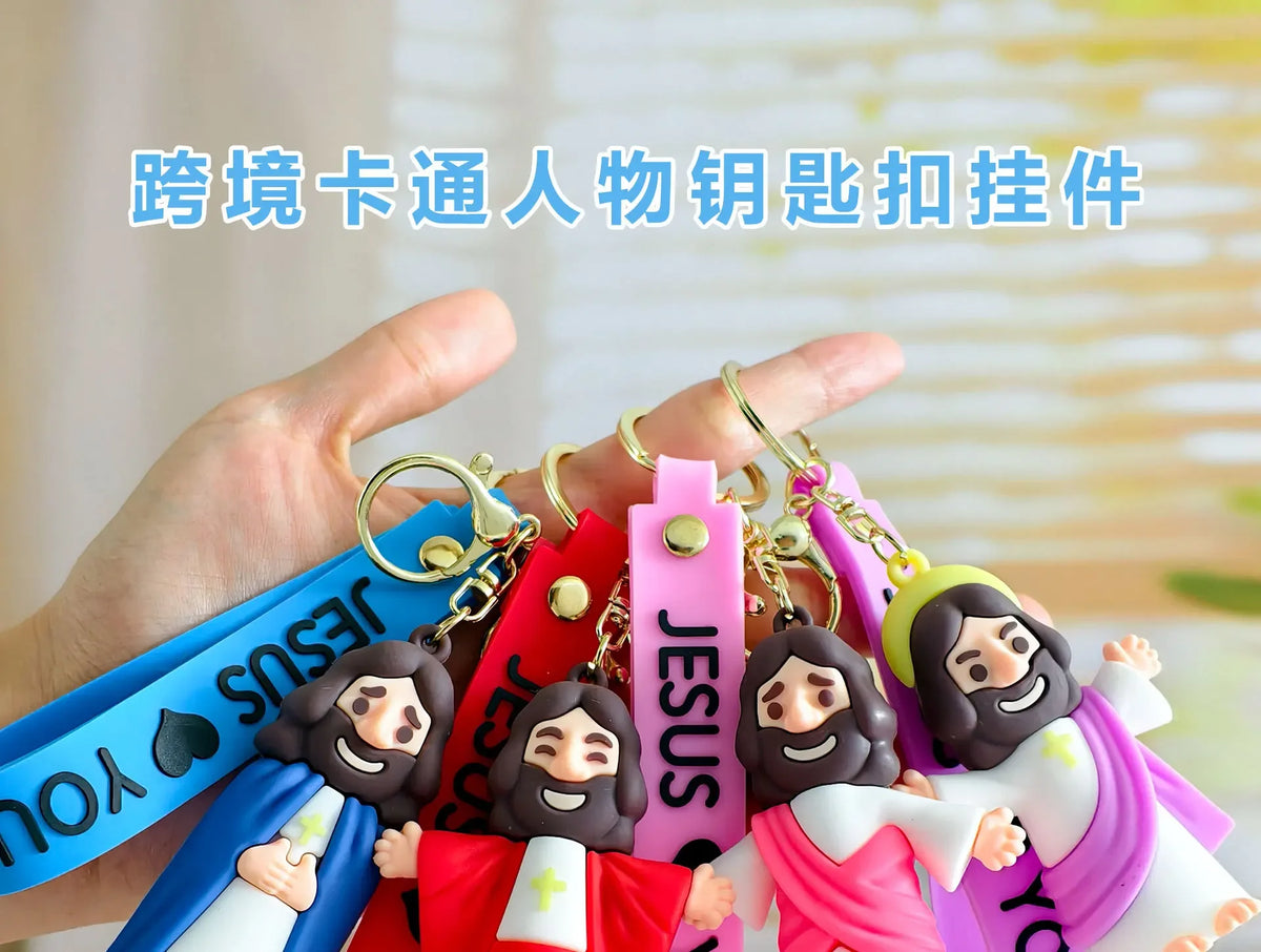 A hand holds a collection of cute silicone Jesus keychains with colorful straps.