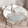 A round marble print tablecloth with an elastic edge is displayed on a wooden table in a bright room.