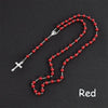 A necklace featuring a silver cross pendant and a string of red beads, resembling a rosary.