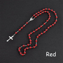 A necklace featuring a silver cross pendant and a string of red beads, resembling a rosary.
