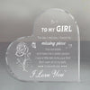 A clear heart-shaped acrylic keepsake engraved with a message to a girl and a rose design.