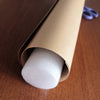 A roll of white foam material is visible inside a cardboard tube, resting on a wooden surface.