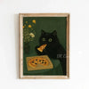 A framed canvas art print featuring a black cat looking intensely at the viewer, with a yellow flower bouquet and a plate of 