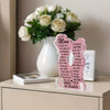 A white ceramic vase holds a bouquet of white roses and a personalized acrylic plaque for Mother's Day gifts.