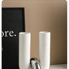 A white ceramic U-shaped tabletop vase with a chrome finish is displayed on a light surface.