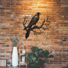 Metal wall art depicting a black raven perched on a bare tree branch against a brick background.