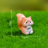 A small, light orange and white miniature animal figurine sitting on green grass.
