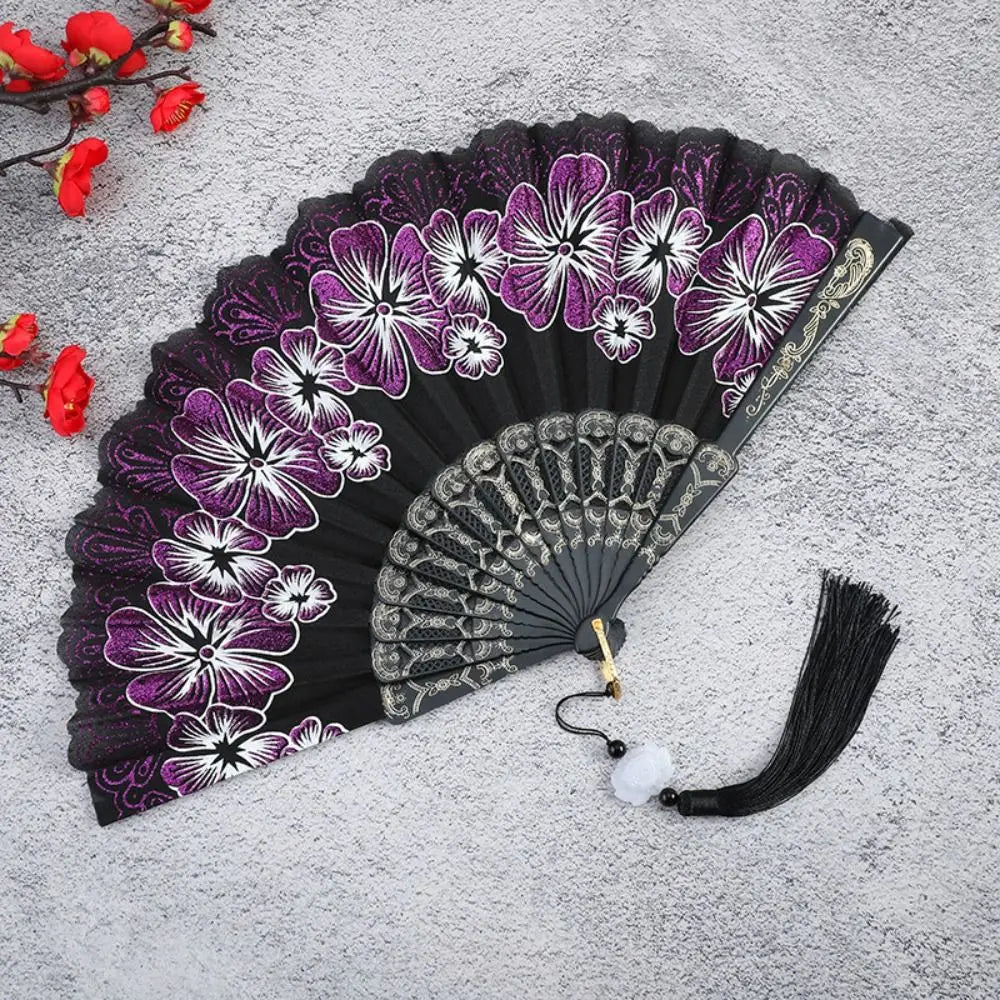 A black folding fan decorated with purple and white floral patterns on the silk surface