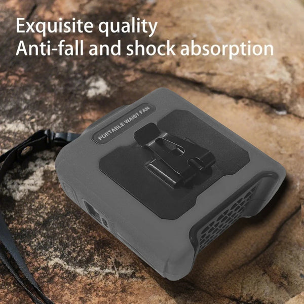 A portable waist fan with a built-in flashlight resting on a rough stone surface.