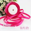 Pink silk satin ribbon rolled up and laid out on a white background