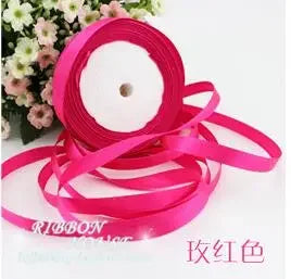 Pink silk satin ribbon rolled up and laid out on a white background