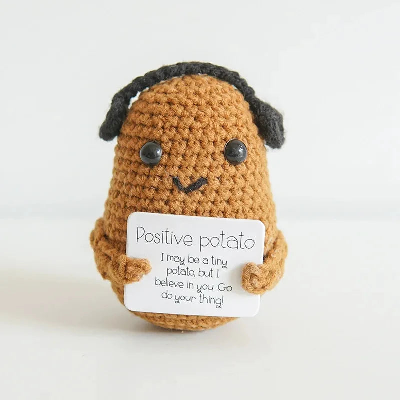 Handmade crochet potato doll with dark hair holding a card that says I may be a tiny potato but I believe in you go do your t