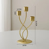 A gold-colored iron candle holder with three slender arms and a round base, shown against a light background.