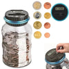 A clear jar filled with coins and a digital coin counting piggy bank with an LCD display and coin slots.