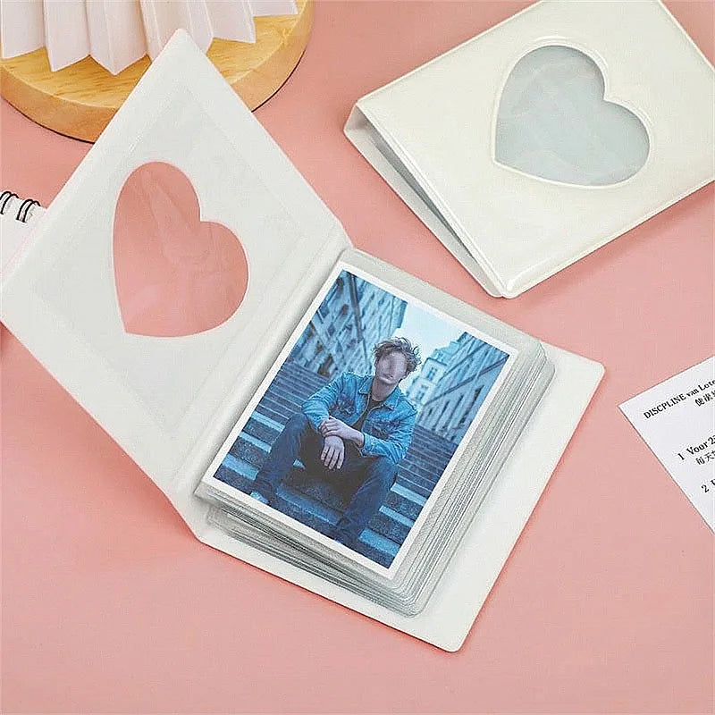 A white photocard album with a heart-shaped window displaying a photo of a person, set on a pink background.