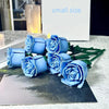 A small bouquet of blue rose flower building blocks displayed on a dark surface.