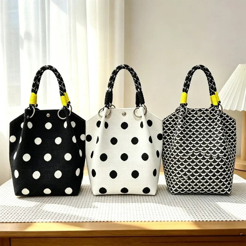 Three black and white polka dot woven shoulder bags with yellow handles displayed on a light surface.