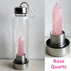 Botella de agua de vidrio transparente con un cristal de cuarzo rosa y un soporte para cristales rosa.