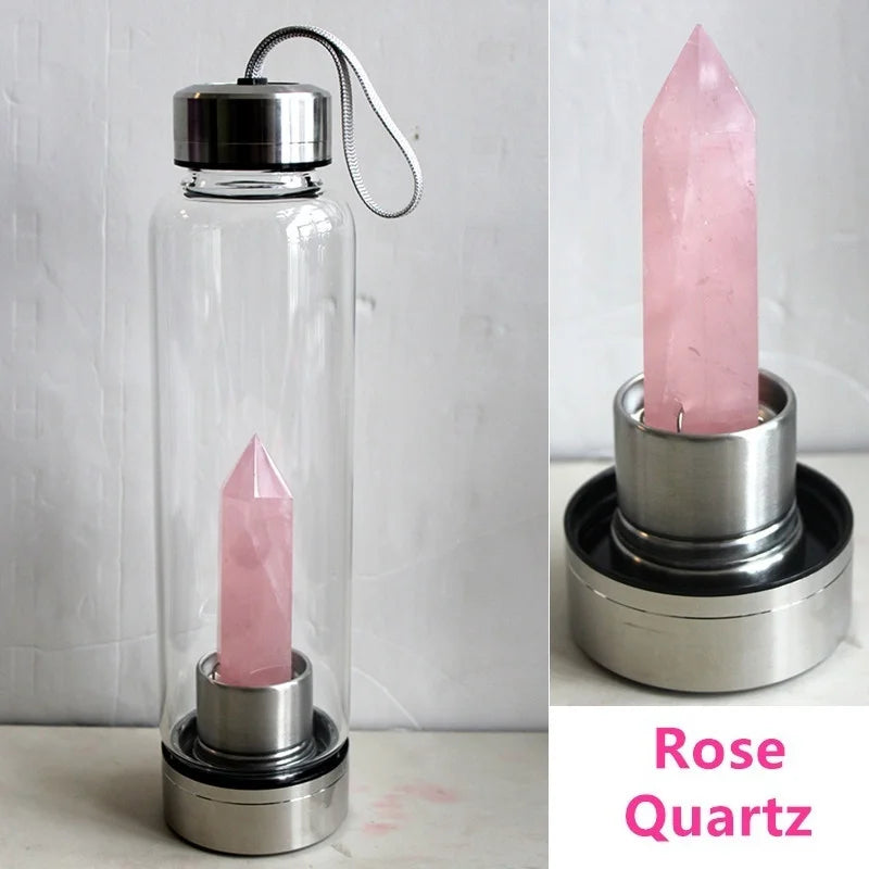 Botella de agua de vidrio transparente con un cristal de cuarzo rosa y un soporte para cristales rosa.