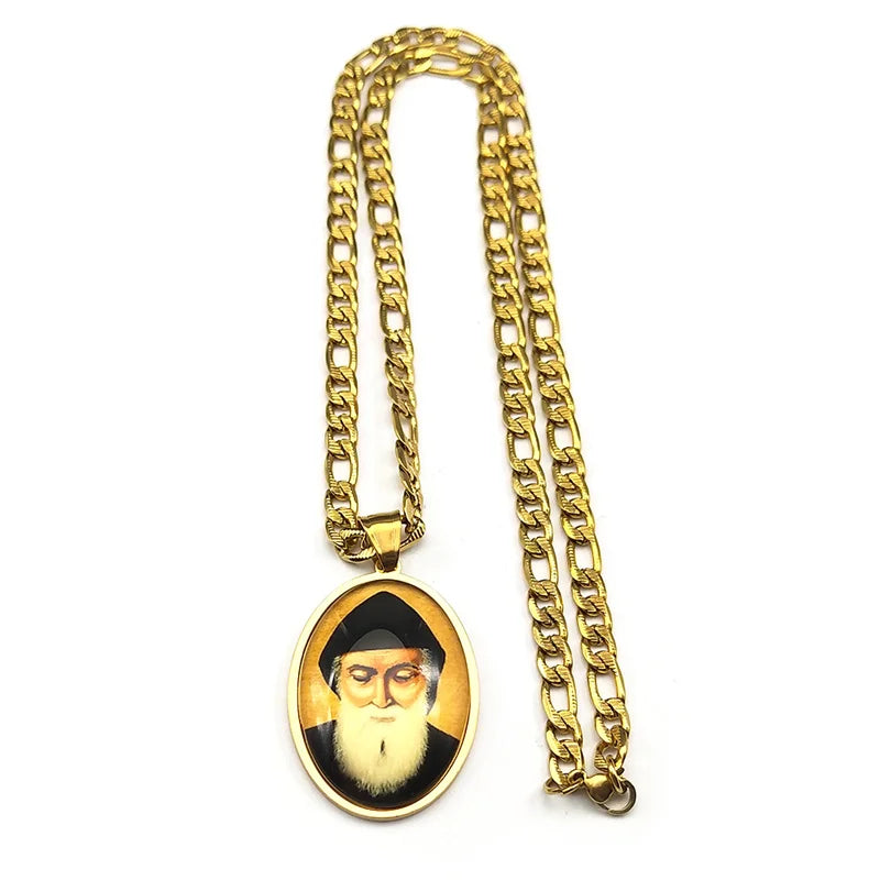 A gold-colored chain necklace with a round pendant featuring a portrait of a man.