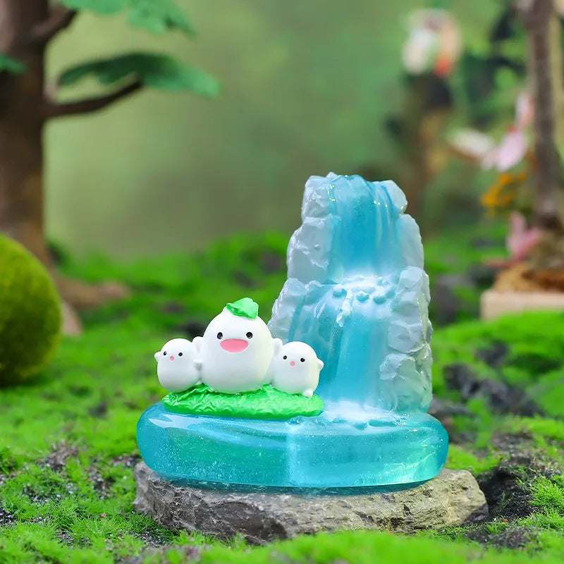 A clear blue glass ornament featuring a white ceramic figurine of two baby birds on a mossy base.