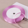 A roll of pink satin ribbon on a white spool, ready for gift wrapping or DIY crafts.