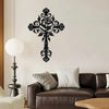 Black metal rose cross wall decor mounted on a white wall above a dark brown sofa.