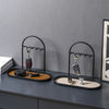 A black wrought iron desk organizer rack holding various leather and metal accessories like pens and cufflinks.